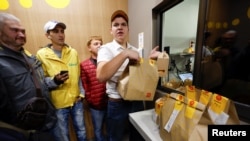 A McDonald's employee passes orders to Glovo food delivery couriers inside a restaurant, after the chain reopened amid Russia's ongoing invasion of Ukraine, in Kyiv, Ukraine, Sept. 20, 2022. 