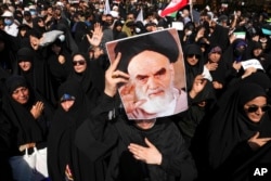 A pro-government demonstrator holds a poster of the late Iranian revolutionary founder Ayatollah Khomeini while attending a rally in Tehran, Iran, Sept. 23, 2022.