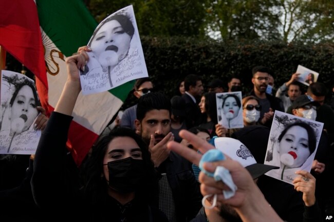 Demonstrators hold placards outside the Iranian Embassy in London, Sunday, Sept. 25, 2022.