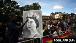 Seorang seniman menunjukkan lukisan Ratu Elizabeth II yang ia buat ketika mengantre di area Kastil Windsor, pada 19 September 2022. (Foto: Pool via AP/Carl de Souza)