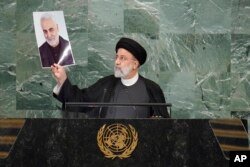 President of Iran Ebrahim Raisi holds up a photo of slain Iranian Gen. Qassem Soleimani, as he addresses the 77th session of the United Nations General Assembly, at U.N. headquarters, Sept. 21, 2022.