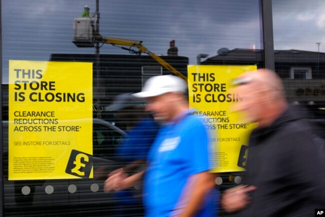 Pedestrians pass a closing down shop in London, Sept. 23, 2022.