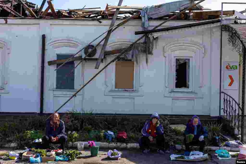 Warga setempat menjual sayuran dekat bangunan pasar yang rusak di Balakliia, wilayah Kharkiv, yang baru saja direbut kembali oleh Angkatan Bersenjata Ukraina.