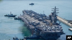 Kapal induk AS USS Ronald Reagan dikawal saat tiba di Busan, Korea Selatan, Jumat, 23 September 2022. (Foto: AP)