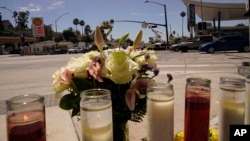 Flowers and candles are left on an intersection after after crash involving as many as six cars near a gas station in the unincorporated Windsor Hills in Los Angeles, Friday, Aug. 5, 2022. (AP Photo/Damian Dovarganes)
