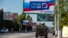 Rusko vojno vozilo prolazi ulicom pored bilborda na kom piše "Sa Rusijom zauvek, 27. septembar", pred referendum u Lugansku, teritoriji pod kontrolom proruskih separatista, u ističnoj Ukrajini, 22. septembra 2022.