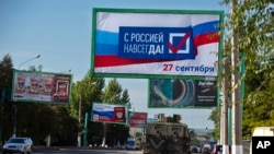 Un vehículo militar se desplaza por una calle con un cartel que dice: "Con Rusia para siempre, 27 de septiembre", antes de un referéndum en Lugansk, República Popular de Lugansk controlada por separatistas respaldados por Rusia, este de Ucrania, 22 de septiembre de 2022.