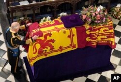 FILE - King Charles III places the Queen's Company Camp Colour of the Grenadier Guards on the coffin at the Committal Service for Queen Elizabeth II, held at St. George's Chapel in Windsor Castle, Sept. 19, 2022. (Jonathan Brady/Pool Photo via AP)