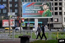 FILE - A billboard promoting contract army service with an image of a serviceman and the slogan reading "Serving Russia is a real job" is seen on display in St. Petersburg, Sept. 20, 2022.