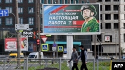 Sebuah papan bergambar seorang prajurit dan slogan bertuliskan "Melayani Rusia adalah pekerjaan nyata" terlihat dipajang di St. Petersburg, 20 September 2022. Seorang petugas wajib militer Rusia telah diskors karena keliru merekrut ribuan orang untuk berperang. (Foto: AFP)