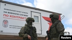 Lính Nga trong trang phục ngụy trang và đeo mặt nạ đen đứng cạnh một xe tải tuyển dụng di động ở Rostov-on-Don, Nga, ngày 17/9/2022.