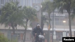 A man on a bicycle rides past in the heavy rain and wind caused by Typhoon Nanmadol in Miyazaki on Japan's southernmost main island of Kyushu September 18, 2022, in this photo taken by Kyodo. (Kyodo via Reuters) 