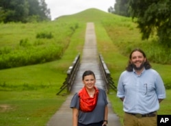 Tracie Revis, left, a citizen of the Muscogee Creek Nation, and Seth Clark, mayor pro-tem of Macon, stand at the approach to the Earth Lodge, where Native Americans held council meetings for 1,000 years until their forced removal in the 1820s, Aug. 22, 2022.
