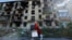 A member of an electoral commission walks past a destroyed building with a mobile ballot box and documents while visiting local residents on the third day of a referendum on the joining of the self-proclaimed Donetsk People's Republic (DPR) to Russia, in 