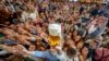 Young people reach out for free beer in one of the beer tents on the opening day of the 187th Oktoberfest beer festival in Munich, Germany, Sept. 17, 2022. 