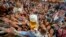 Young people reach out for free beer in one of the beer tents on the opening day of the 187th Oktoberfest beer festival in Munich, Germany, Sept. 17, 2022. 