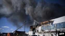 Sejumlah petugas pemadam kebakaran berusaha memadamkan api yang melalap gedung pasar international Rungis di Rungis, di selatan Paris, pada 25 September 2022. (Foto: AFP/Christophe Archambault)