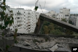 A window frame hangs off the edge of a residential building that was damaged after a Russian attack in Kharkiv, Ukraine, Wednesday, Sept. 21, 2022. (AP Photo/Leo Correa)