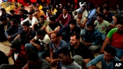 Migrants sit on the deck after being rescued by the Spanish NGO Open Arms lifeguards during a rescue operation in the international waters zone near Tunisia, Mediterranean sea, Saturday, Sept. 17, 2022. Fifty-nine migrants from Syria, Egypt, Sudan and Eri