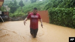 Un hombre camina por una calle inundada por el huracán Fiona en Cayey, Puerto Rico, el domingo 18 de septiembre de 2022. (Foto AP/Stephanie Rojas)