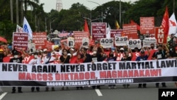 Protesters carry placards as they march during a rally to commemorate 50 years anniversary of the imposition of martial law at the university grounds in Quezon City, suburban Manil, Philippines, Sept. 21, 2022.