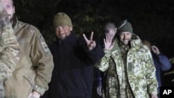 En esta imagen publicada por la Oficina de Prensa del Servicio de Seguridad de Ucrania, soldados ucranianos liberados en un canje de prisioneros entre Rusia y Ucrania sonríen cerca de Chernígov, Ucrania, la noche del miércoles 21 de septiembre de 2022 (Oficina de Prensa del Servicio de Seguridad de Ucrania via AP)