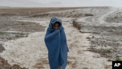FILE - A 9-year-old Afghan girl labor stands in the rain near a brick factory, where she works on the outskirts of Kabul, Afghanistan, Aug. 20, 2022.