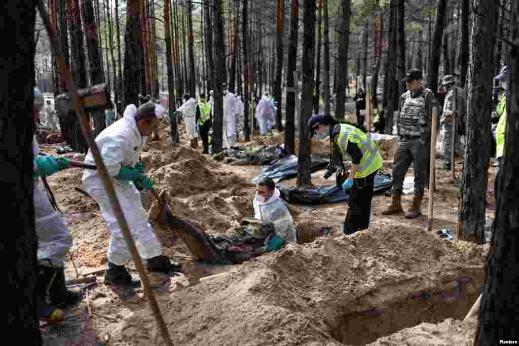 Experts work at a forest grave site during an exhumation in the town of Izium, recently liberated by Ukrainian Armed Forces in Kharkiv region.