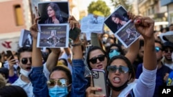 Women hold up pictures of Iranian Mahsa Amini as they shout slogans during a protest against her death, outside Iran's consulate general in Istanbul, Turkey, Sept. 21, 2022. 