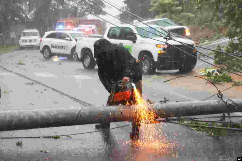 Un trabajador corta un poste de electricidad que fue derribado por el huracán Fiona y bloqueaba una carretera en Cayey, Puerto Rico, el domingo 18 de septiembre de 2022. (Foto AP/Stephanie Rojas)