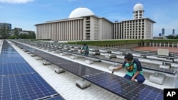 Workers perform maintenance work on solar panels that provide partial electrical power to Istiqlal Mosque in Jakarta, Indonesia, March 29, 2023. 