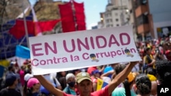 ARCHIVO - Un simpatizante del gobierno sostiene un cartel con un mensaje que dice en español: "En unidad contra la corrupción", durante un mitin contra la corrupción, en Caracas, Venezuela, el sábado 25 de marzo de 2023.