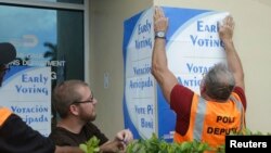 Petugas menempel poster mengenai pemilihan umum lebih awal di Miami-Dade, Florida (12/10). (AP/Lynne Sladky)