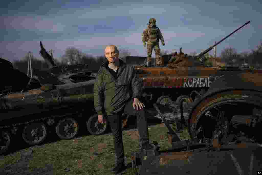 Un civil con una máscara con la imagen de Putin mientras un soldado ucraniano sube a un tanque ruso destruido en Bucha, a las afueras de Kiev, Ucrania, el 7 de abril de 2022.