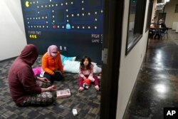 Christopher Harris, left, his wife Novi, center, and their daughter Keeva occupy an office suite at a pop-up warming center in Richardson, Texas, Feb. 16, 2021.
