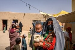 FILE - A woman who fled her village in Helmand province when it was taken over by the Taliban, waits to see a doctor at a mobile clinic for women and children set up near Lashkar Gah in Helmand province, Afghanistan, March 28, 2021.