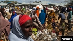 FILE - Somali refugees organize their collected ration of food during a distribution exercise outside a United Nations World Food Program center at a refugee settlement in Dadaab, Kenya, October 2013.