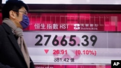 A man walks past a bank's electronic board showing the Hong Kong share index at Hong Kong Stock Exchange, Jan. 7, 2021.