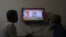 Two people watch a televised address to the nation by Prime Minister Narendra Modi on economic stimulus measures, in Hyderabad, India, May 12, 2020.