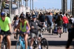 People ride their bikes along a bike bath near the pier, March 21, 2020, in Huntington Beach, Calif. California Governor Gavin Newsom issued a statewide stay at home order for Californians in an attempt to slow the spread of the coronavirus.
