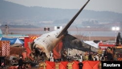 Bombeiros e membros da equipa de resgate trabalham junto aos destroços de um avião de passageiros no Aeroporto Internacional de Muan, em Muan, Coreia do Sul, a 29 de dezembro de 2024.