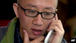 FILE - Chinese dissident Hu Jia talks on his phone during a meeting at a restaurant in Beijing, April 10, 2013.