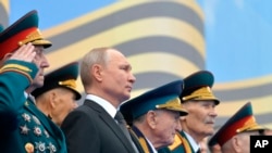 FILE - Flanked by World War II veterans, Russian President Vladimir Putin watches a military parade marking 74 years since the end of World War II, in Red Square, in Moscow, Russia, May 9, 2019.