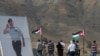 FILE - Jordanian visitors walk next to a poster depicting Jordanian King Abdullah during their visit to Baquora area in Jordanian border side, in the border area between Jordan and Israel, Nov. 13, 2019. 