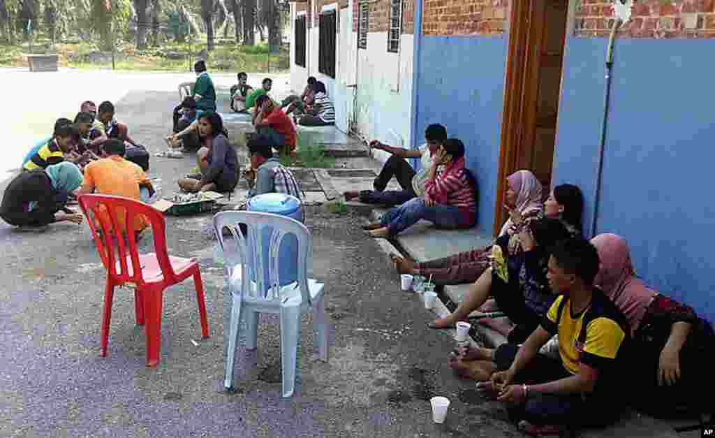 In this photo released by Malaysian Fire and Rescue Department, Indonesians rest on Carey Island after being rescued from a capsized boat, June 18, 2014.