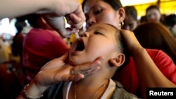 FILE - A child receives free polio vaccine during a government-led mass vaccination program.