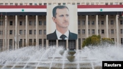 FILE - A picture of the Syria's President Bashar Assad is seen on the central bank building in Damascus, Feb. 24, 2012. 