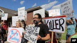 Warga berdemonstrasi di depan tempat praktik dokter gigi Walter Palmer di Bloomington, Minnesota (29/7), memprotes pembunuhan singa Cecil di Zimbabwe oleh Palmer. (AP/Ann Heisenfelt)