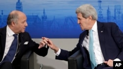 French Foreign Minister Laurent Fabius, left, chats with U.S. Secretary of State John Kerry on the podium during the 51st Munich Security Conference in Germany, Feb. 8, 2015. 