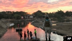 A Mexican National Guard looks at local residents crossing the Suchiate River, near Ciudad Hidalgo, on the Mexican border with Guatemala, Jan. 17, 2020. 